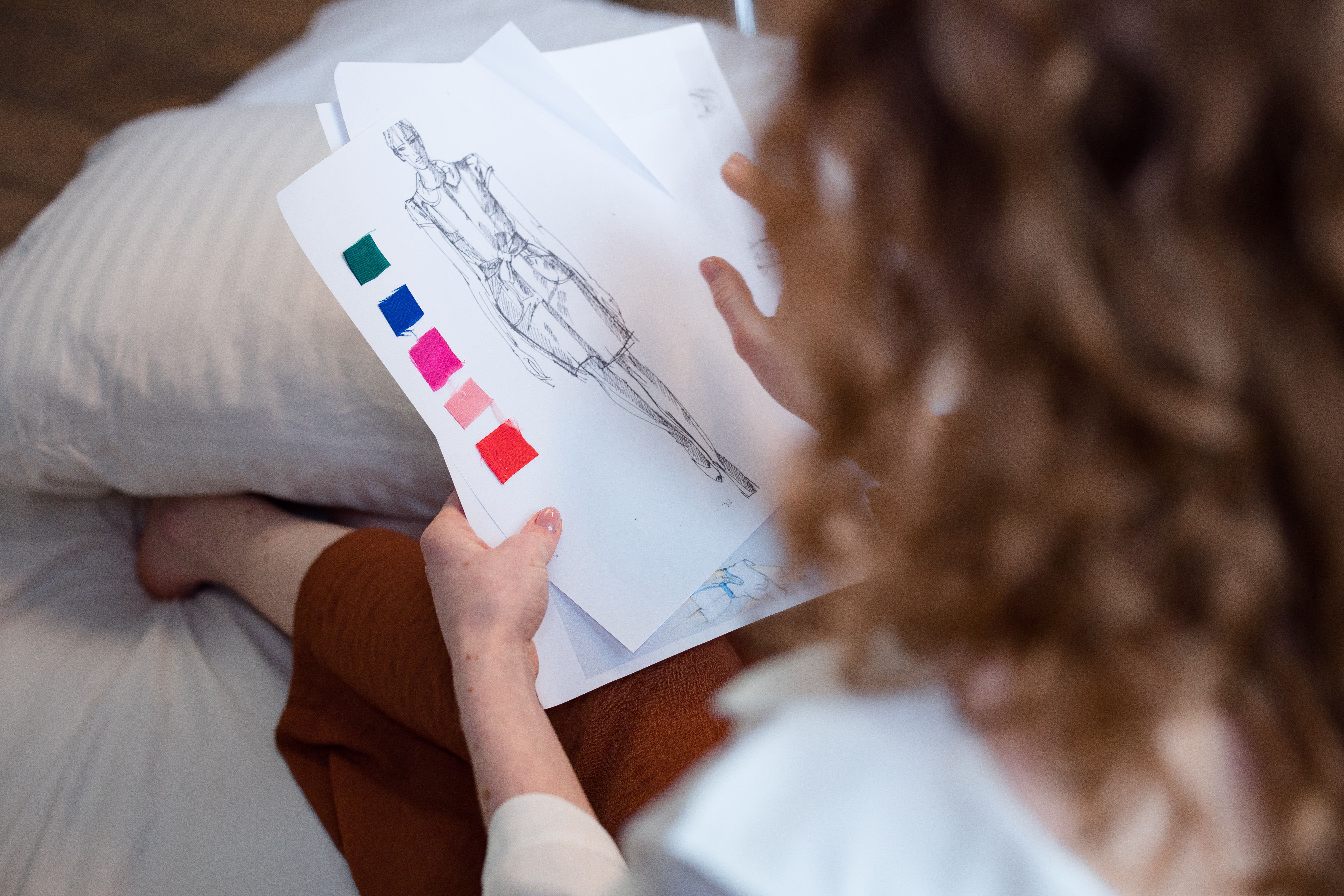 Fashion designer evaluating fabric samples and garment sketches