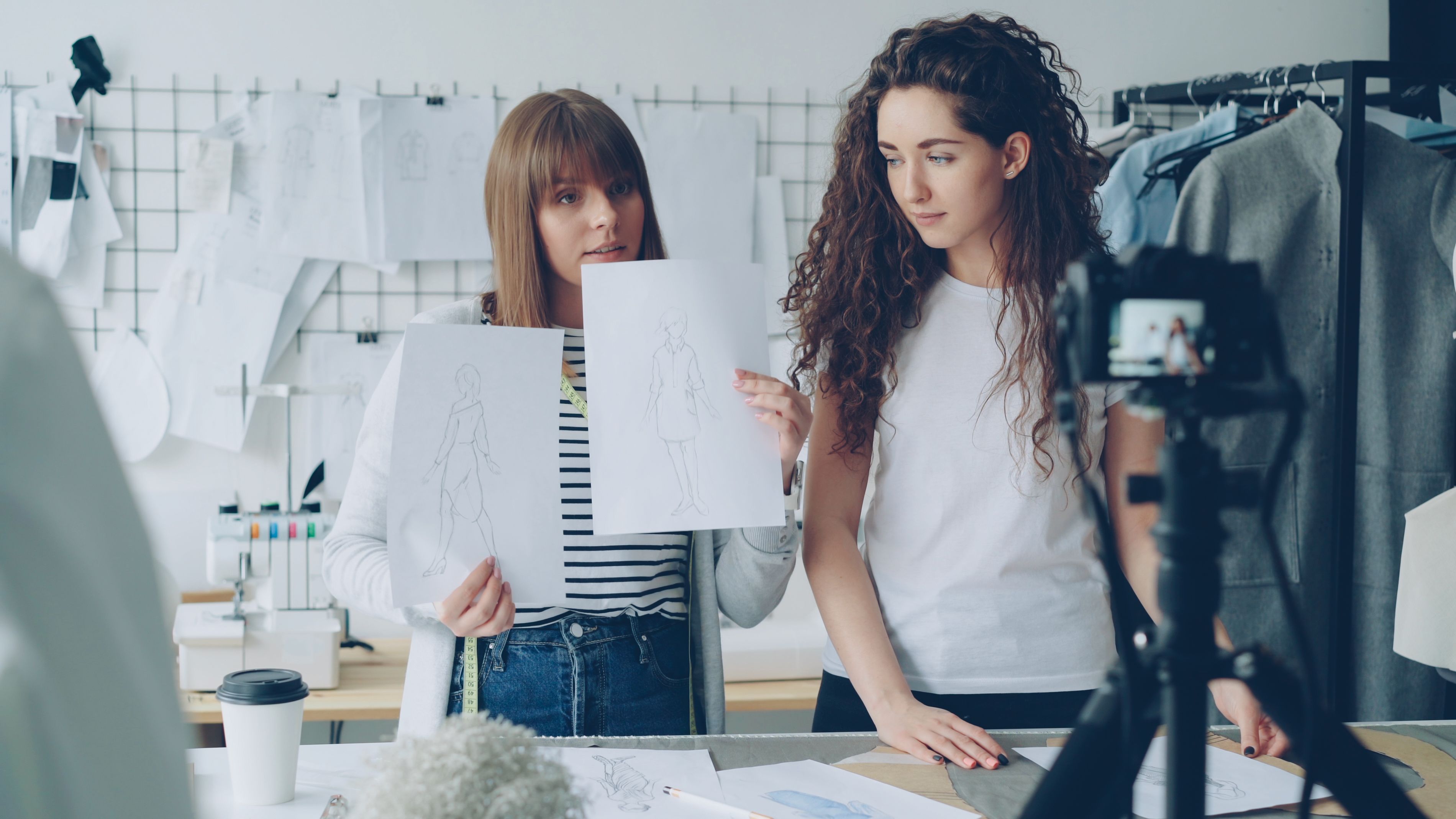 Two fashion designers reviewing garment sketches together in a studio