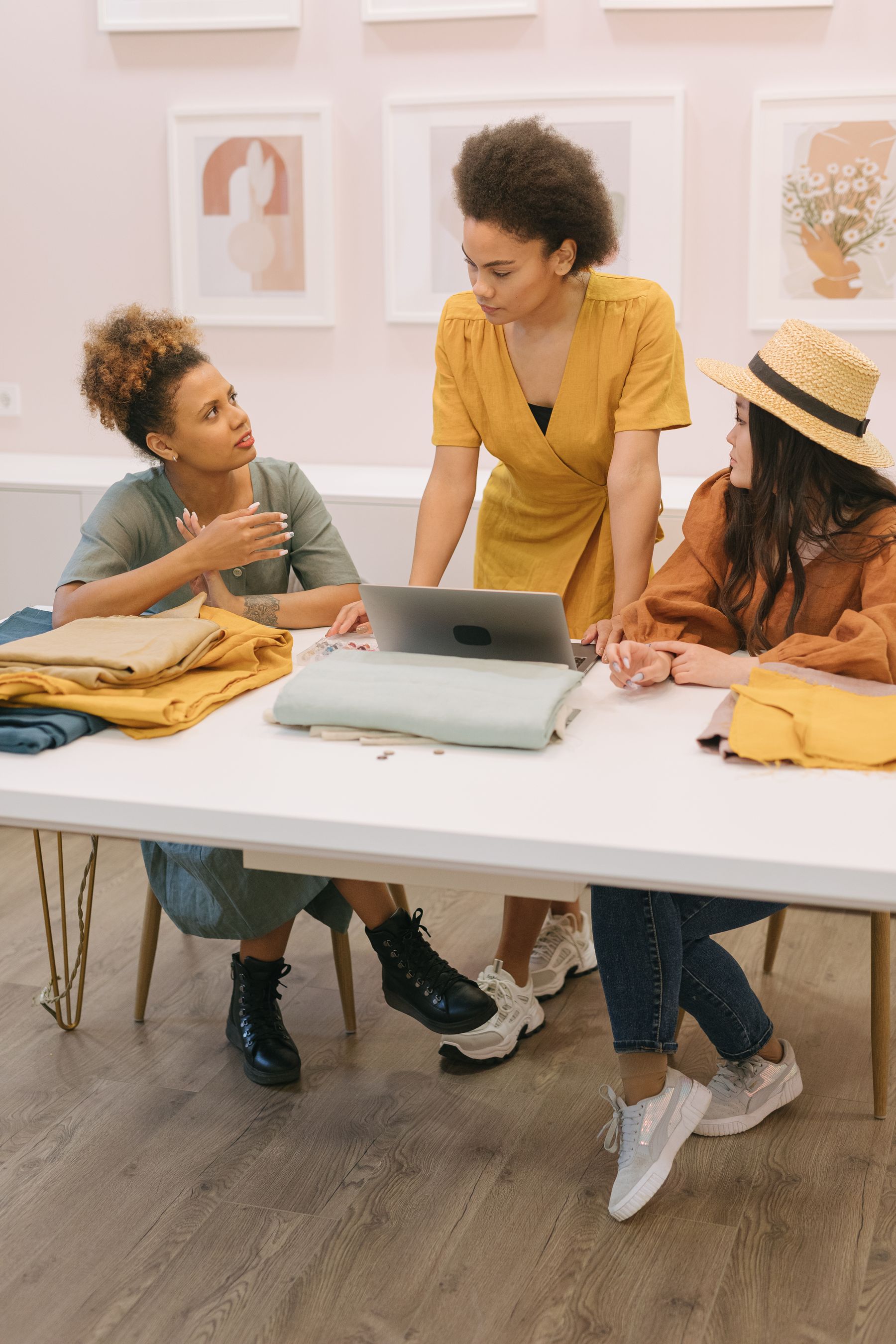 Fashion professionals coordinating garment orders with fabric samples and a laptop