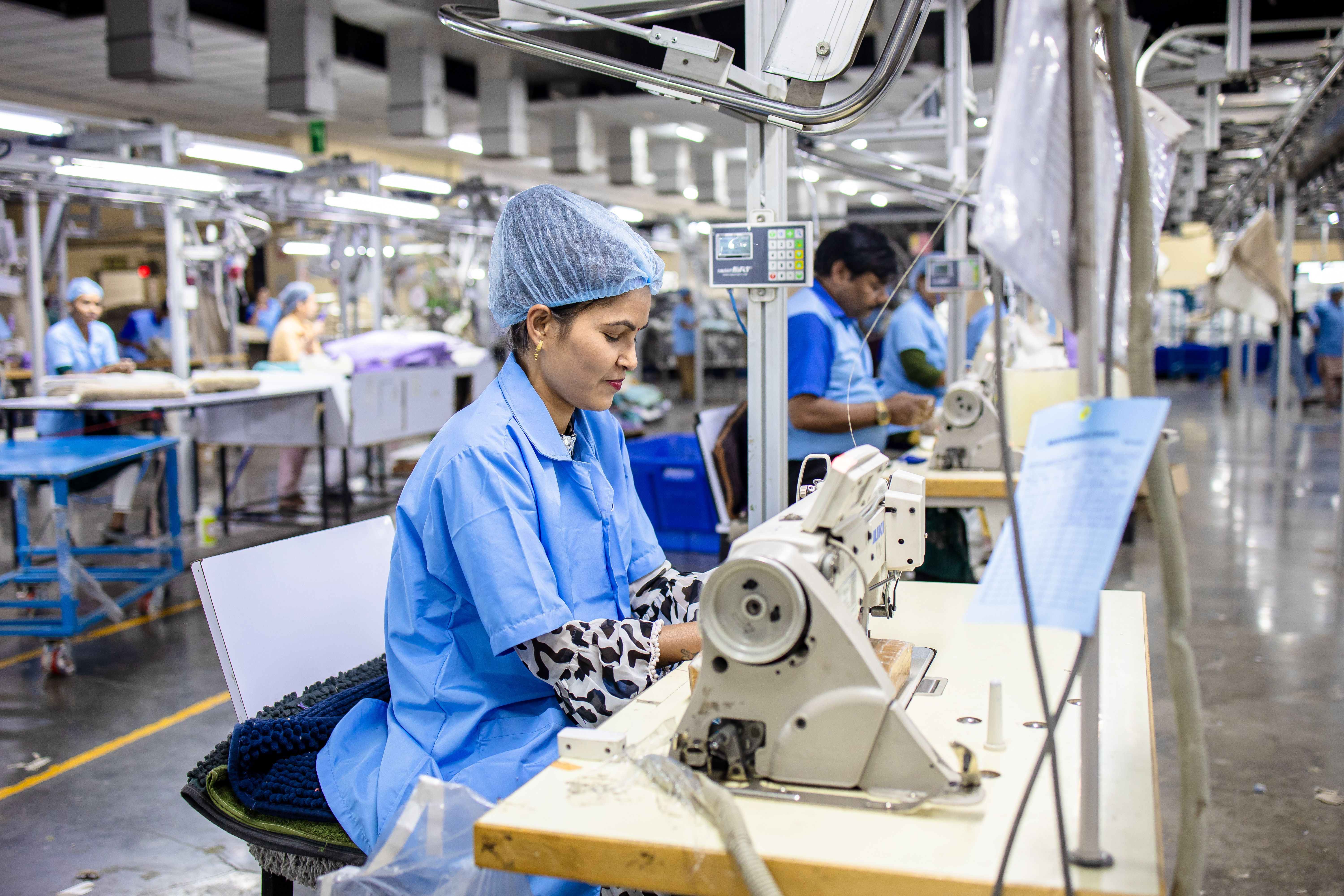 Garment employees operating industrial sewing machines across a production line
